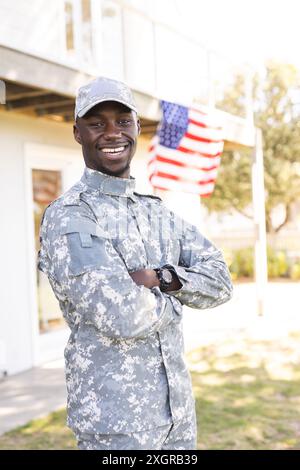Portrait d'heureux soldat afro-américain en uniforme debout à l'extérieur de la maison souriant, espace de copie. Service militaire, armée, maison, vie domestique et Banque D'Images