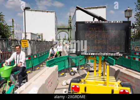 Cyclistes utilisant une voie cyclable temporaire pour traverser un pont Hammersmith encore fermé dans le sud-ouest de Londres, Angleterre, Royaume-Uni Banque D'Images