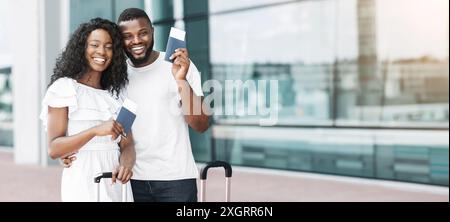 Couple souriant tenant des passeports à l'aéroport avant le départ Banque D'Images