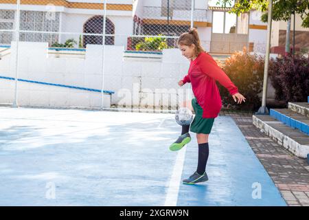 Concepts : sports féminins et loisirs de plein air. jeune femme jouant au football en milieu urbain. exercice et mode de vie actif Banque D'Images