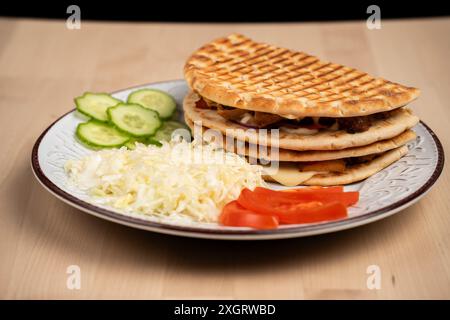 Une assiette de sandwichs pita grillés avec chou râpé, tranches de concombre et tranches de tomates Banque D'Images