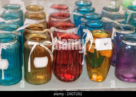 Des vases en verre coloré sont vendus en magasin. Bocaux pour fleurs. Banque D'Images