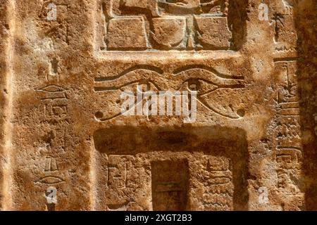 Fragment de mur en pierre égyptienne antique avec des symboles d'yeux sculptés Banque D'Images