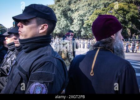 Un policier regarde la foule qui est venue assister à la parade du jour de l’indépendance, tandis qu’un ecclésiastique de l’Église orthodoxe russe regarde passer les groupes militaires. Dans la ville de Buenos Aires, vers 11h00, le défilé du 9 juillet, jour de la déclaration de l'indépendance de la République Argentine, a eu lieu. L'acte a été présidé par le Président Javier Milei, accompagné de ses principaux responsables. Les vétérans de la guerre des Malvinas menaient le défilé. (Photo de Rosana Alvarez Mullner/SOPA images/SIPA USA) Banque D'Images