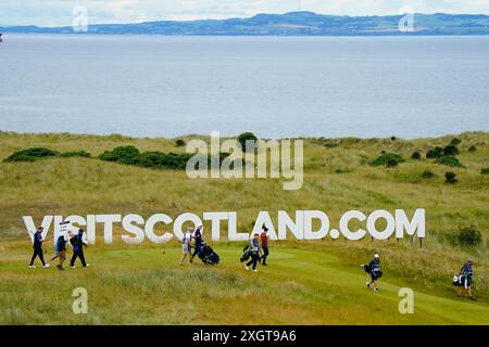 Gullane, Écosse, Royaume-Uni. 10 juillet 2024. Journée de pratique Pro Am au Genesis Scottish Open qui commence le jeudi 11 juillet jusqu'au 14 juillet au Renaissance course à l'extérieur de Gullane dans East Lothian. Pic ; les joueurs marchent devant le grand panneau Visit Scotland au 12ème trou. Iain Masterton/Alamy Live News Banque D'Images