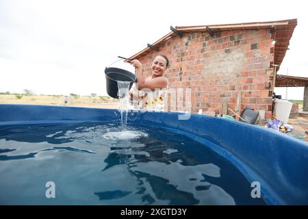 Rodelas, bahia, brésil - 15 juin 2024 : une femme recueille l'eau d'un réservoir d'eau dans la zone rurale de la ville de ​​the, Rodelas. Banque D'Images