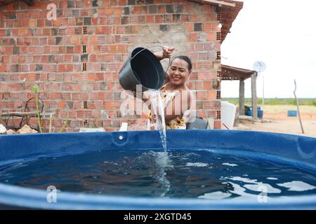 Rodelas, bahia, brésil - 15 juin 2024 : une femme recueille l'eau d'un réservoir d'eau dans la zone rurale de la ville de ​​the, Rodelas. Banque D'Images