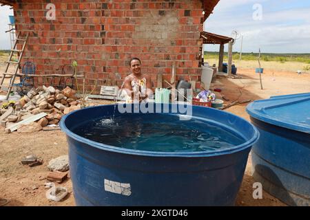 Rodelas, bahia, brésil - 15 juin 2024 : une femme recueille l'eau d'un réservoir d'eau dans la zone rurale de la ville de ​​the, Rodelas. Banque D'Images