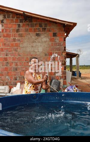 Rodelas, bahia, brésil - 15 juin 2024 : une femme recueille l'eau d'un réservoir d'eau dans la zone rurale de la ville de ​​the, Rodelas. Banque D'Images