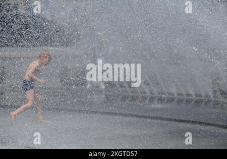 Munich, Allemagne. 10 juillet 2024. Un garçon court à travers les fontaines d'eau de Stachus. Crédit : Sven Hoppe/dpa/Alamy Live News Banque D'Images