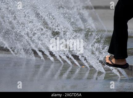 Munich, Allemagne. 10 juillet 2024. Une femme tient le pied dans les fontaines d'eau de Stachus. Crédit : Sven Hoppe/dpa/Alamy Live News Banque D'Images