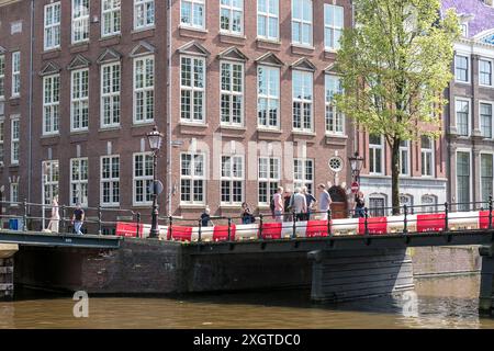 Les gens se rassemblent par un canal par une journée ensoleillée à Amsterdam, aux pays-Bas. Banque D'Images