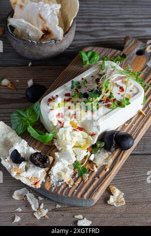 Un morceau de feta frais (paneer) avec des olives, des herbes, des épices et des tranches de pain plat (tortilla, lavash, pitta, chapatti) sur une planche en bois et un d Banque D'Images