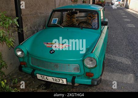 Trabant vert rouillé avec de fausses housses de siège en peau de tigre, garé dans une rue à Tábor, Bohême du Sud, Tchéquie, en 2006. La Trabant, lancée en 1957, est parfois qualifiée de « pire voiture de tous les temps ». Elle est devenue une voiture emblématique en 1989 avec la chute du mur de Berlin et reste une voiture culte en Allemagne. Ce Trabant a un faux badge BMW et un autocollant « International Truck Driver » sur le capot ou le capot et un permis de stationnement pour personnes handicapées sur le pare-brise. Banque D'Images