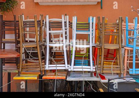 Piles de chaises et de tables en bois colorées à l'envers devant le café-restaurant Banque D'Images