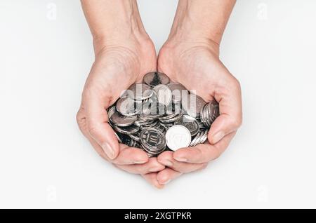 Les mains féminines tiennent beaucoup de pièces d'argent dans leurs paumes Banque D'Images