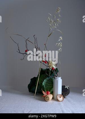 Un arrangement de bon goût mettant en vedette du chou de savoie, un radis noir et de minuscules pommes de crabe rouge, rehaussant l'attrait artistique de cette nature morte Banque D'Images