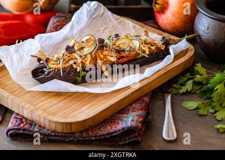 Du haut aubergine farcie cuite chargée de tomates cerises, poivrons, oignons, ail, tranches de pommes de terre, et fromage, garni de microgreens, serv Banque D'Images