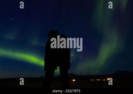 Jeune couple en voyage de lune de miel profitant d'aurores vertes dans le nord de l'Islande Banque D'Images