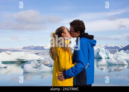 Un moment romantique capturé par un couple de baisers, encadré par la magnifique toile de fond des icebergs et des eaux claires en Islande Banque D'Images