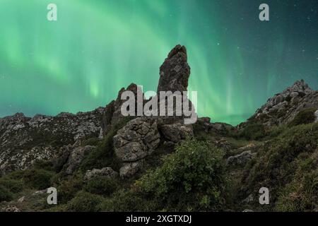 Un magnifique ciel nocturne printanier illuminé par les teintes vibrantes des aurores boréales, sur fond de montagnes escarpées et de terrains rocheux Banque D'Images