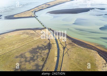 Cette photographie aérienne capture une vue imprenable sur une route côtière en Islande, mettant en valeur l'interaction fascinante entre la terre et l'eau avec le plongeur Banque D'Images