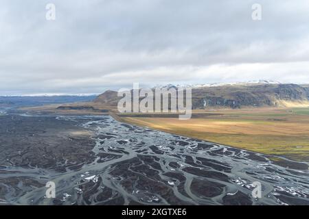 Photo aérienne captivante du terrain unique de l'Islande avec rivières tressées, prairies tentaculaires et montagnes escarpées aux calottes enneigées lointaines Banque D'Images