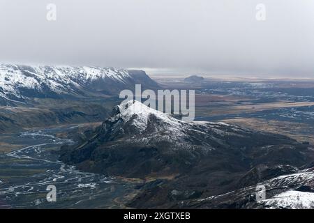 Une photo aérienne panoramique capturant les majestueuses montagnes enneigées et la rivière sinueuse qui coule à travers le terrain accidenté du paysage islandais, il Banque D'Images