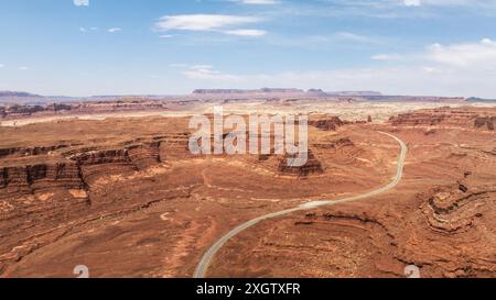 Une photo aérienne panoramique capture le paysage accidenté de la Vallée des Dieux dans l'Utah, aux États-Unis, avec une route sinueuse au milieu d'imposantes formations rocheuses Banque D'Images