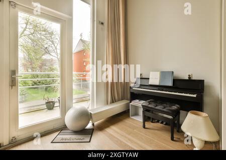 Un salon bien éclairé et confortable avec un piano droit, de grandes fenêtres avec une vue panoramique sur le jardin, et une ambiance sereine à Amsterdam, quartier Henkenshage Banque D'Images