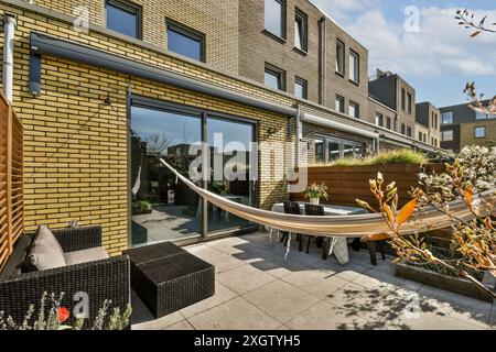 Vue extérieure résidentielle contemporaine de Jan Vrijmanstraat 98, avec un patio ensoleillé avec un hamac, des sièges confortables et un gar bien entretenu Banque D'Images