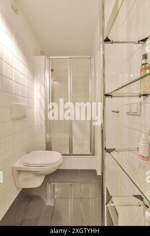 Une salle de bains moderne soigneusement agencée avec un design carrelé blanc, une douche en verre fermée et des équipements minimalistes se trouve à Jan Weilandlaan, Netherlan Banque D'Images