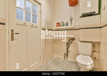 Une salle de bains confortable de style vintage avec des toilettes blanches classiques, des carreaux de métro et des éléments décoratifs rétro. Banque D'Images