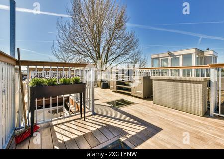 Un patio contemporain sur le toit avec une cuisine extérieure élégante, équipée d'un barbecue et de rangements. La zone dispose d'une terrasse en bois, boîte de plantation Banque D'Images