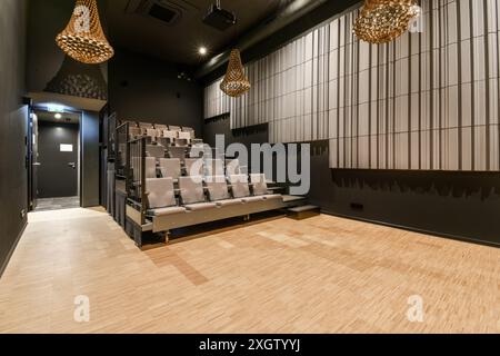 Un élégant Home Cinéma privé au design intérieur contemporain avec des sièges à plusieurs niveaux confortables, des suspensions saisissantes et un mur géométrique Banque D'Images