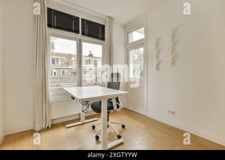 Un bureau à domicile moderne et lumineux au style minimaliste, avec un bureau blanc, une chaise de bureau et des stores. Banque D'Images