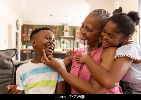 Senior afro-américaine profite d'un moment ludique à la maison avec ses petits-enfants. Leur rire crée une atmosphère chaleureuse et familiale dans le coz Banque D'Images