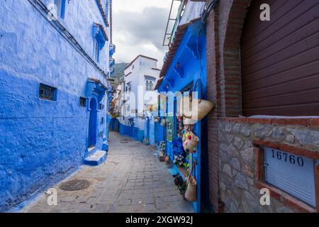 Chefchaouen, Maroc - 25 mars 2024 : une boutique d'artisanat présentant des plaques de céramique colorées et des miroirs dans les rues peintes en bleu. Banque D'Images