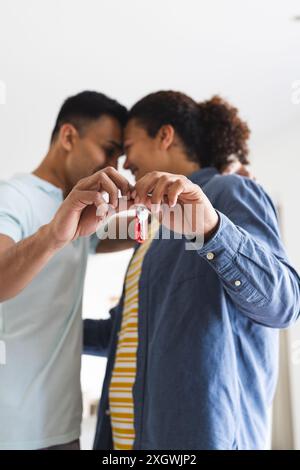 Couple gay biracial tenant une clé ensemble, avec espace de copie. Ils célèbrent une nouvelle maison, symbolisant un nouveau départ et un engagement. Banque D'Images