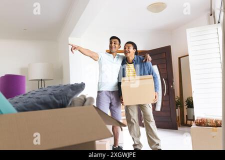 Un homme du moyen-Orient et un jeune homme biracial, un couple gay, explorent leur nouvelle maison. Ils partagent l'excitation des possibilités futures dans leur vie confortable Banque D'Images
