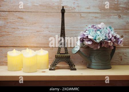 Décoration maison Tour Eiffel, bougie LED et fleur artificielle dans un pot de fleurs sur fond de baie en bois Banque D'Images