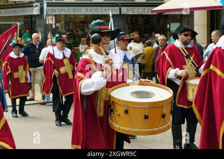 Astorga, Espagne - 4 juin 2023 : un groupe d'hommes, vêtus de rouge et d'or, jouent énergiquement de la batterie ensemble en harmonie synchronisée. Banque D'Images