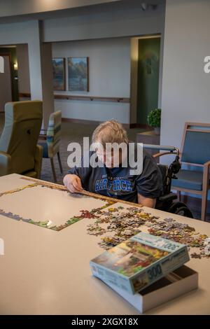 Maplewood, Minnesota. Femme âgée victime d'un accident vasculaire cérébral travaillant sur un puzzle dans la salle communautaire d'une maison de soins infirmiers. Banque D'Images