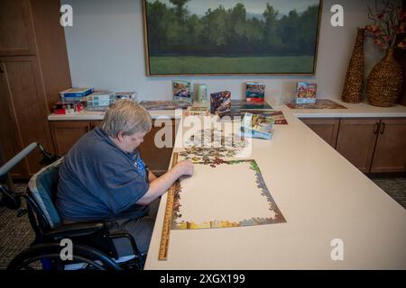 Maplewood, Minnesota. Femme âgée victime d'un accident vasculaire cérébral travaillant sur un puzzle dans la salle communautaire d'une maison de soins infirmiers. Banque D'Images