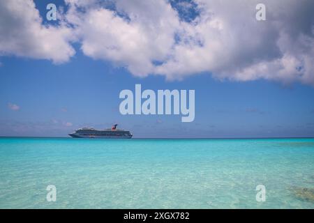 Un bateau de croisière naviguant sur des eaux turquoises lumineuses, vu d'une belle plage par une journée ensoleillée Banque D'Images