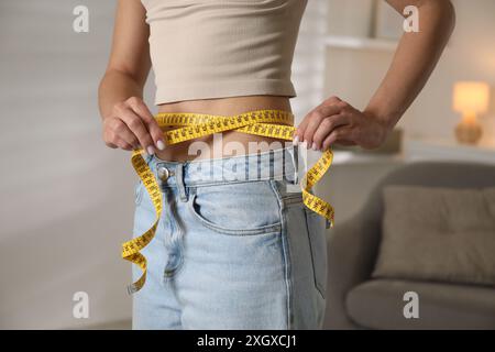 Troubles de l'alimentation. Femme mesurant sa taille à l'intérieur, gros plan Banque D'Images