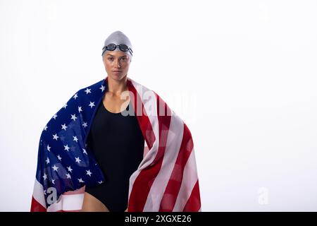 Nageuse féminine enveloppée dans le drapeau américain, avec un espace de copie sur fond blanc. La jeune femme caucasienne respire la confiance et la fierté nationale. Banque D'Images