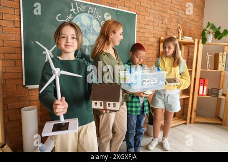 Adolescent avec éolienne et modèle de maison dans la salle de classe. Concept d'écologie Banque D'Images