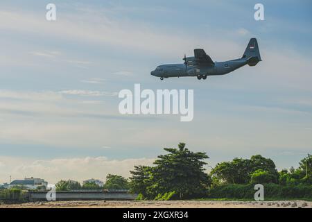Balikpapan, Indonésie - 14 juin 2024. Un avion de transport militaire Lockheed C-130J Hercules survole une belle plage au vert luxuriant Banque D'Images