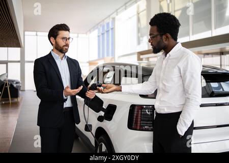 Concessionnaire vend SUV électrique à l'homme d'affaires dans la concession automobile moderne Banque D'Images